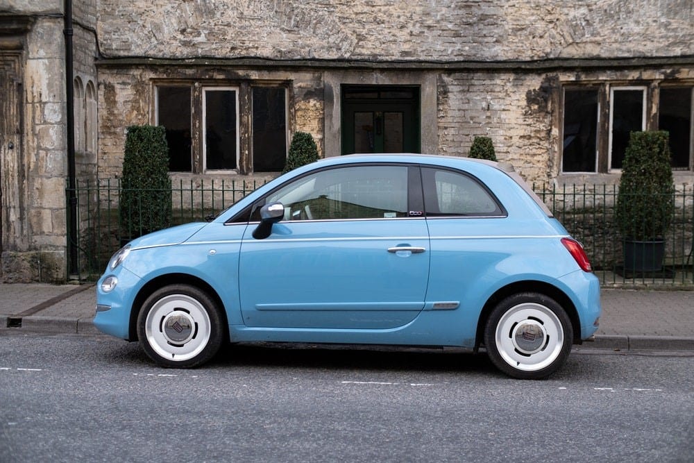 A blue car out of the front of someone's house